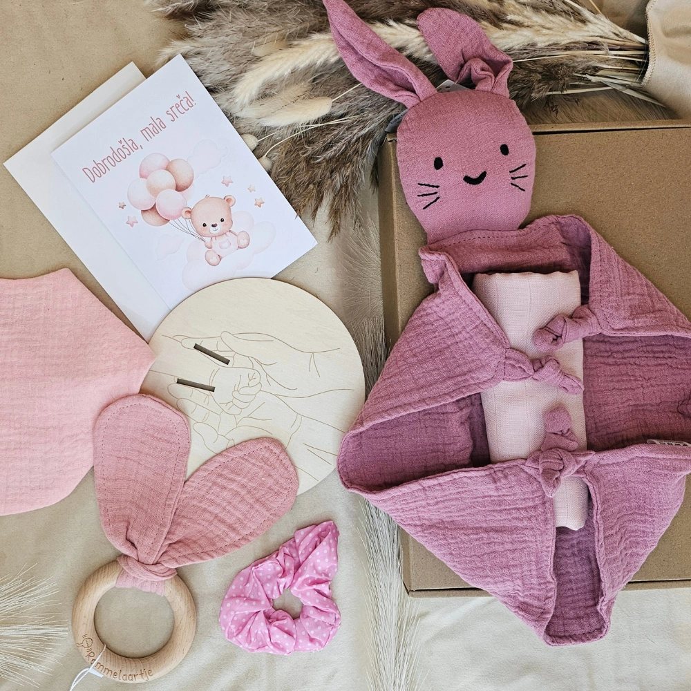 paket za darilo ob rojstvu za novorojenčka zajčkov objem z ninico, ploščico, čestitko, elastiko in tetra pleničko v roza barvi, grizalom in slinčkom